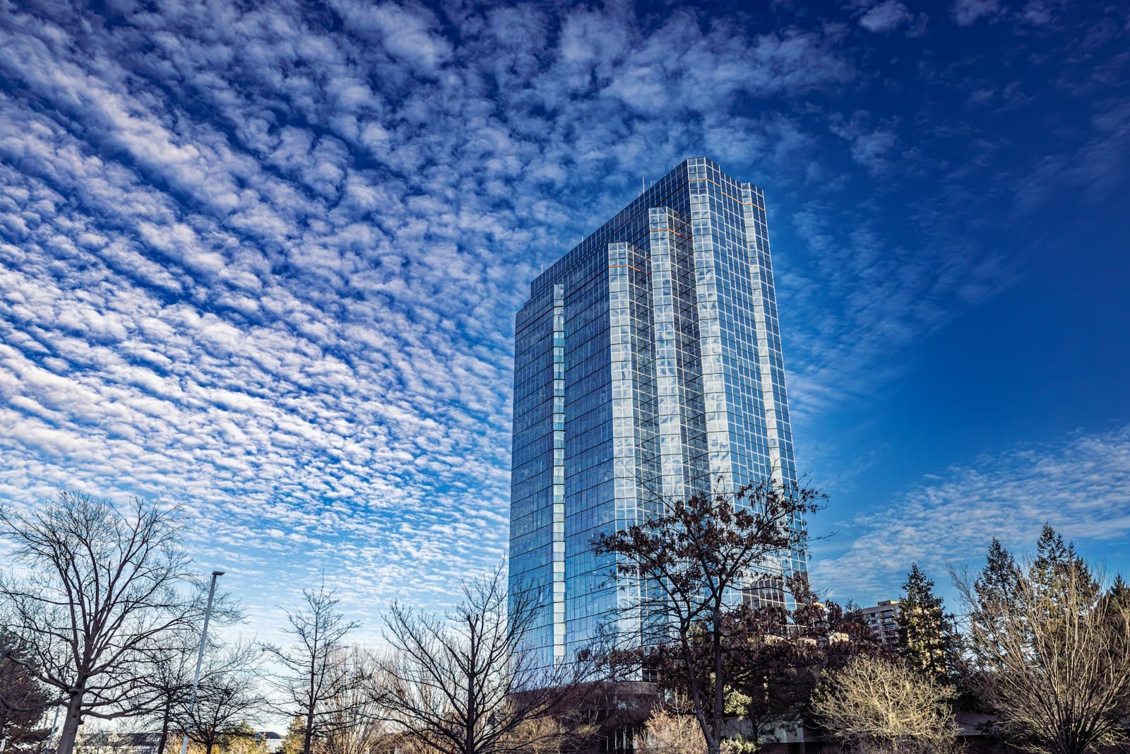 Modern all-glass residential high-rise against a clear sky.