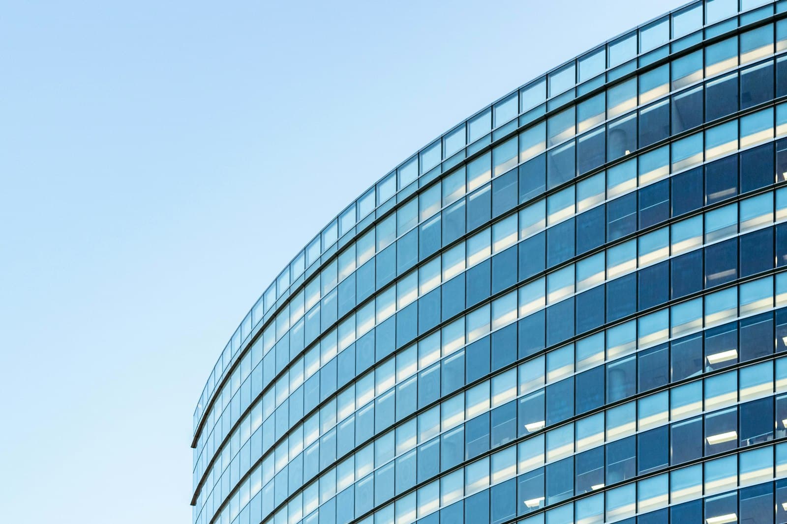 Curved blue-glass office tower facade on a sunny day.