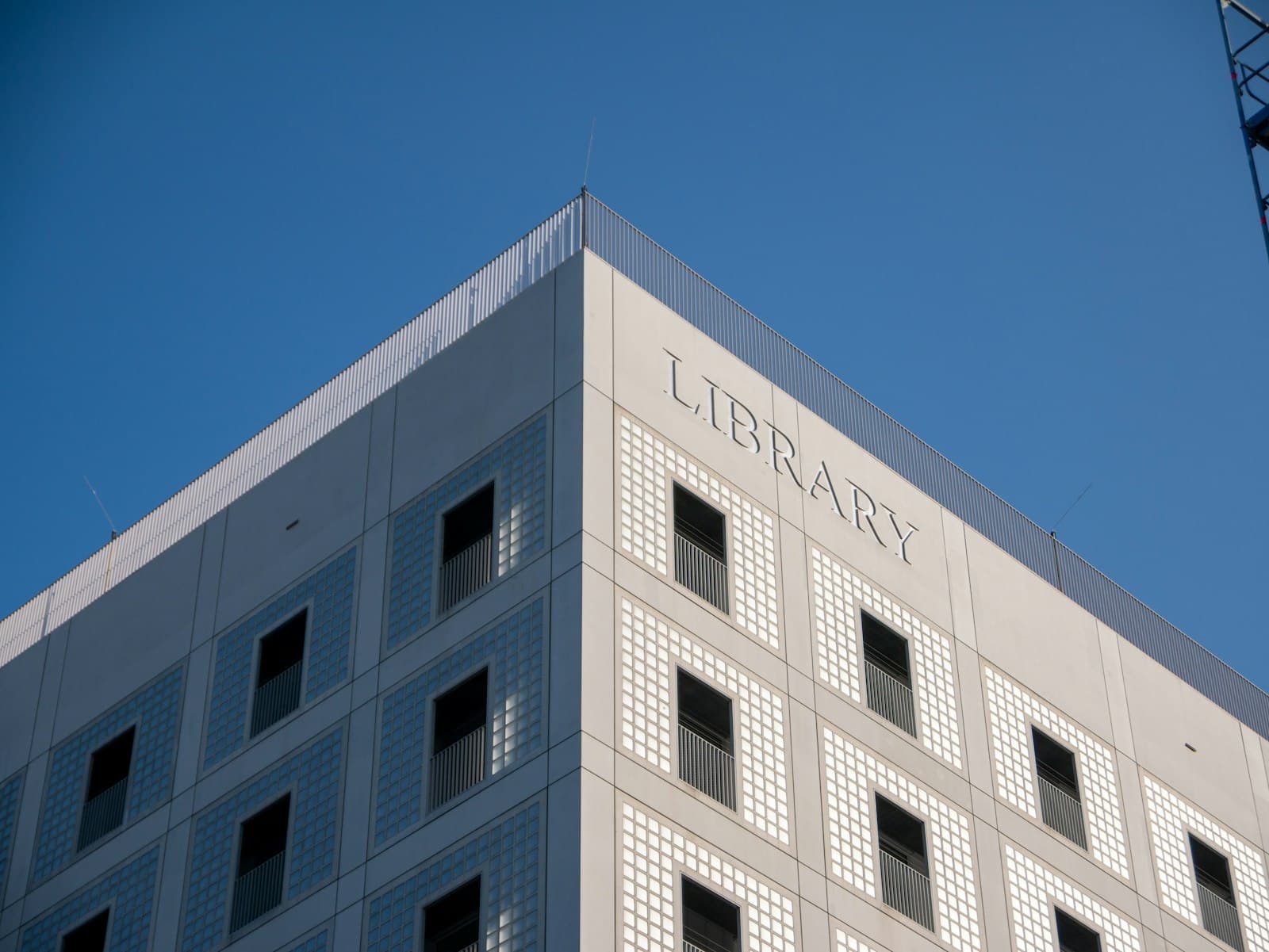 Modern public library building corner against a blue sky.